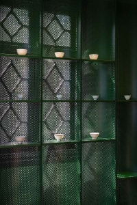 A modern interior design featuring perforated metal shelving with small white bowls.