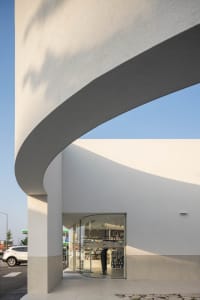 Modern retail storefront with concrete facade and curved entrance.