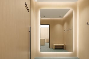 A minimalist wooden wardrobe with clothing hooks and seating.