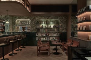 A modern bar and cafe interior featuring marble, concrete, and leather materials.