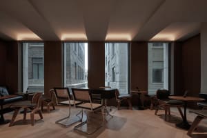 Modern office cafe space with wooden furniture and concrete columns.