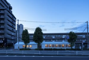 A modern commercial building with brick exterior and glass windows at dusk.