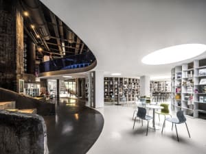 Industrial-style library with concrete and metal materials, featuring seating and bookshelves.