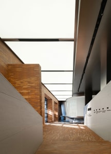 Interior view of an industrial-style office lobby featuring brick walls, metallic accents, and large glass windows.