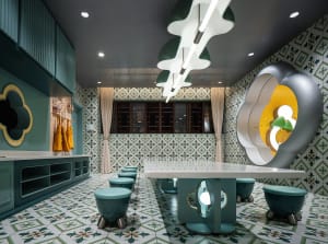 A modern restaurant interior with a tile floor, green and white color scheme, and unique lighting fixtures.