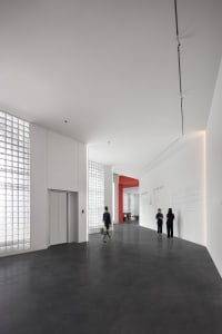 A spacious, minimalist lobby with a concrete floor and walls, featuring large windows.