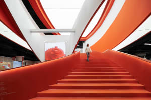 A modern, orange staircase with a curved railing in a contemporary design setting.
