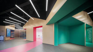 A vibrant classroom and exhibit hall space with multicolored walls and gray flooring, featuring modern design elements.