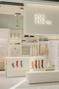 A retail store showcasing clothing on shelves and racks, with a minimalist design.