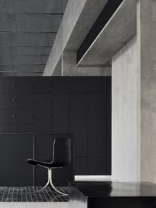 A modern storefront with concrete walls and a sleek, black chair.