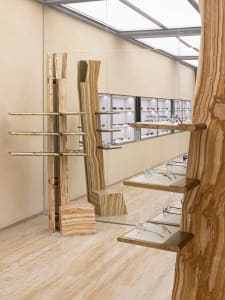 A modern retail space featuring wooden shelves and display cases filled with eyeglasses.