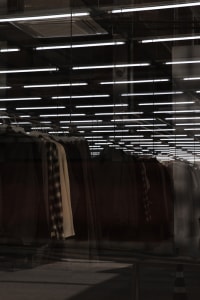 Clothing items hanging on racks in a glass-walled retail display