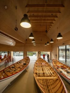 Modern boat storage interior with wooden boats and hanging lights.