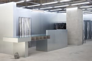 Modern minimalist clothing retail store interior with metallic finishes and industrial design elements.