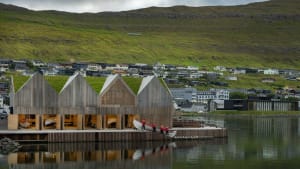 Modern wooden architectural design with a grass-covered hillside in the background.
