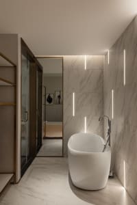 Spacious, modern-style bathroom with a freestanding bathtub, marble walls, and floor, featuring sleek, minimalist design elem