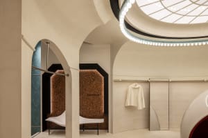 A modern retail store with concrete walls and ceiling, featuring a clothing rack with minimalist white clothes.