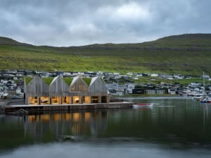 Modern waterfront house with wooden exterior, glass windows, and stone accents.