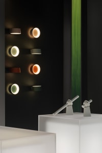 Multiple metal wall-mounted lights of varying colors displayed on a black wall.