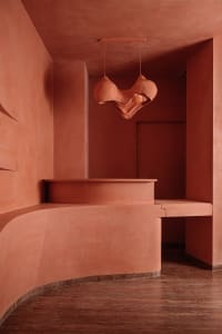 A modern minimalist concrete interior design with a unique hanging lamp and curved seating area.