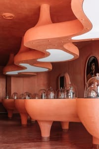A modern shopping center with orange cement walls and lights.