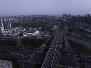 Aerial view of a cityscape featuring a modern highway system with concrete, steel, and glass elements.