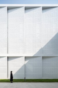 A modern building facade featuring a white perforated metal panel