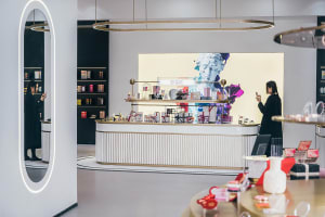 A modern minimalist retail storefront interior with a sleek white and gold color scheme, showcasing various beauty products.