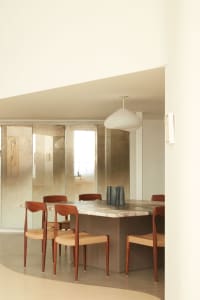A modern dining room featuring a marble table with wooden chairs and a pendant light hanging above.