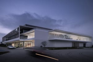 A contemporary building with glass facade and concrete elements at dusk