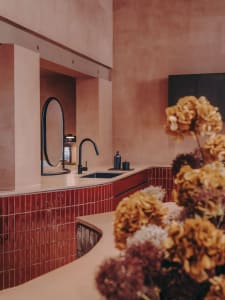 A minimalist bathroom featuring red ceramic tiles and black fixtures