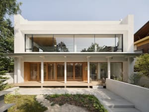 Modern minimalist house with white stucco exterior, large glass windows, and wooden accents.