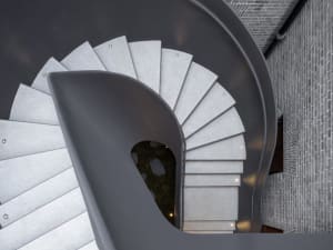 Modern staircase designed in grey concrete with a spiral slide.