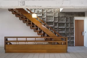 A modern wooden staircase with a concrete wall and surrounding structure.