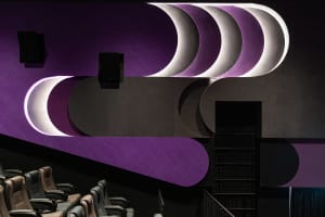 A modern minimalist cinema interior with curved purple and black geometric shapes and seats.