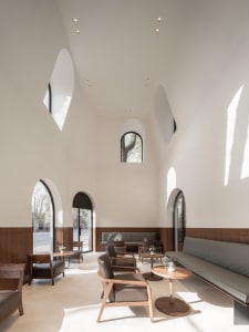 A spacious, modern coffee shop interior with wooden furniture and high ceilings.