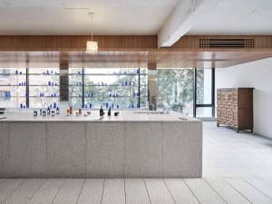A modern retail storefront featuring a marble counter with bottles and vials displayed on shelves.