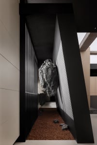 An industrial-style interior design featuring concrete walls and a large rock formation within the space.
