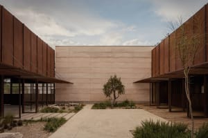 A minimalist building entrance with a concrete wall and pathway leading to the entrance door.