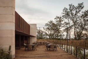 Outdoor seating area of a modern restaurant with wooden tables and metal railings.