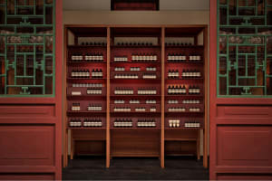 Well-lit retail store interior featuring modern wooden shelves stocked with bottles of products and glass display cases.