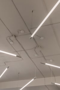 Long modern metallic ceiling lights mounted on white square tiles ceiling