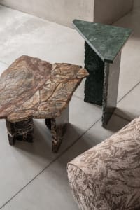 A modern interior design featuring marble side tables on a concrete floor.