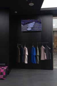 A clothing display with black walls featuring various colors of clothing.