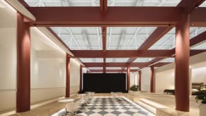 Modern office space featuring red steel beams and white marble tile flooring.