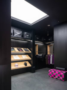 Modern retail store with dark interior, featuring clothing and accessories displayed on shelves.