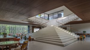 Image of a modern living room with a concrete staircase, glass walls, and wooden accents.