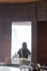 A textured wall paneling restaurant counter with a person standing behind it.