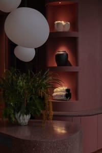 Modern interior design with red shelves displaying ceramic and terrazzo materials.