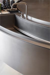 A sleek, minimalist kitchen counter made of stainless steel with a built-in sink and faucet.